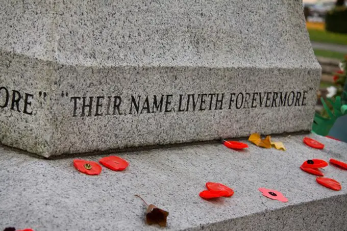 Cenotaph with red poppies on Remembrance Day. Words - Their name liverth forevermore