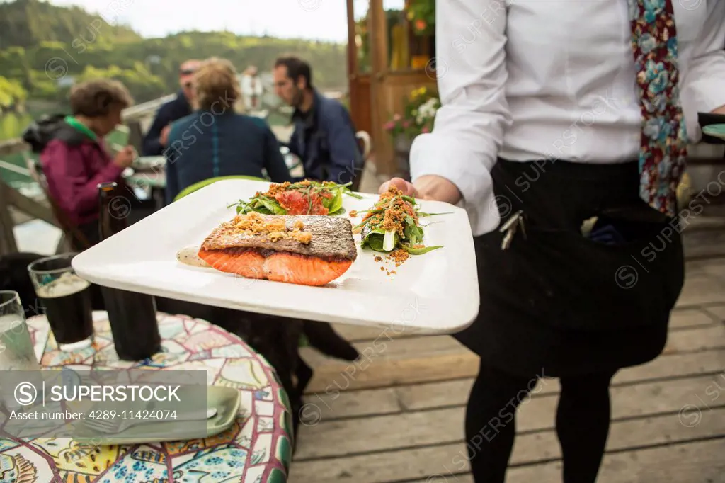 Waitress serves fresh locally caught Sockeye Salmon at The Saltry Restaurant, Halibut Cove, Kachemak Bay, Southcentral Alaska