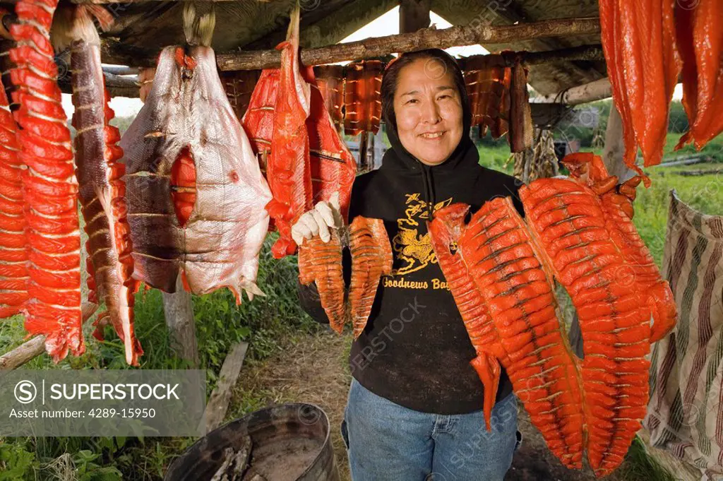 Native Yupik eskimo woman shows off small & large King Salmon fillets @ fish camp Tuluksak WE Alaska