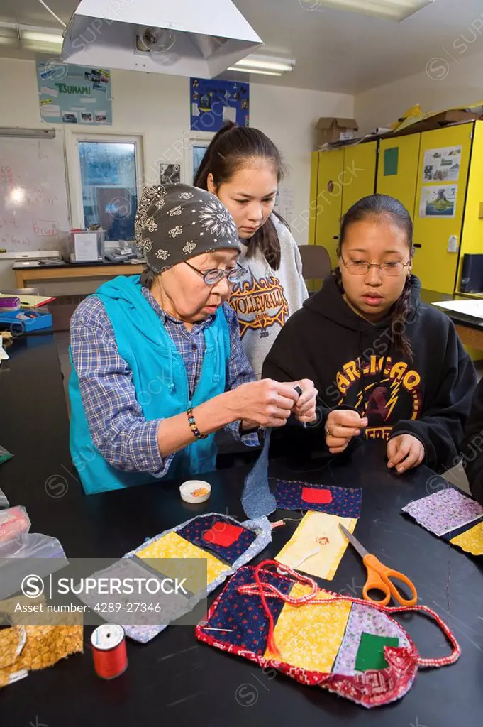 Elder native Yupik woman teaches youth to do bead work @ Akiak High School inside Western Alaska