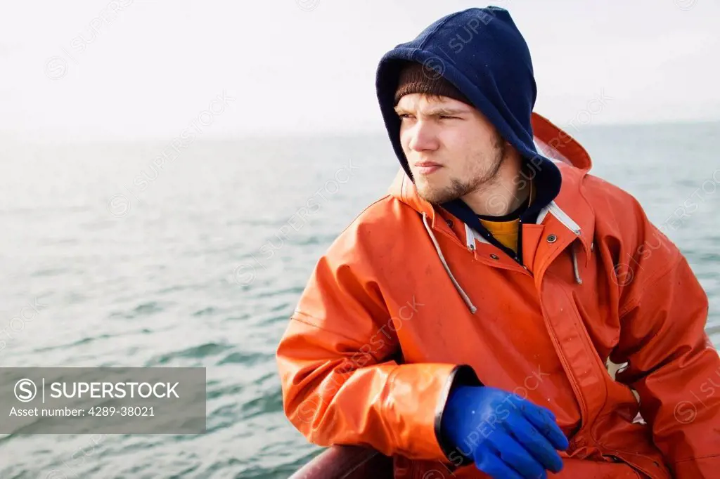 A Rain Gear Clad Deckhand Takes A Break And Sits On The Rail