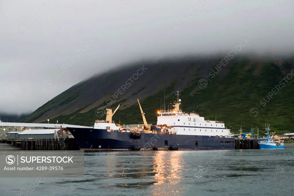 The Stellar Sea, a floating seafood processor, alongside a seafood processing facility dock in King Cove, Alaska Peninsula, Southwest Alaska, summer.