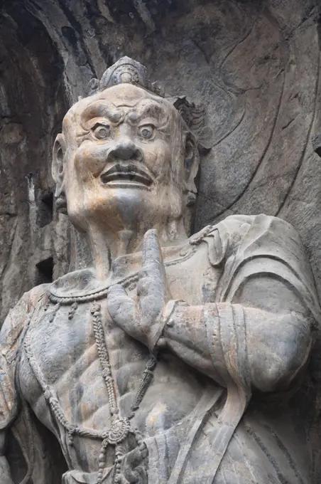 Carved statue, Fengxian Temple, Longmen Grottoes and Caves, Luoyang, Henan Province, China. Tang Dynasty