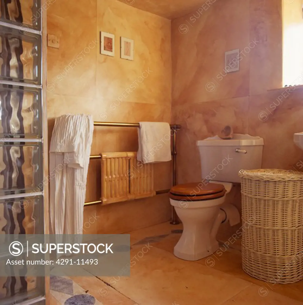 Marble effect painted walls in bathroom with wicker laundry basket beside toilet