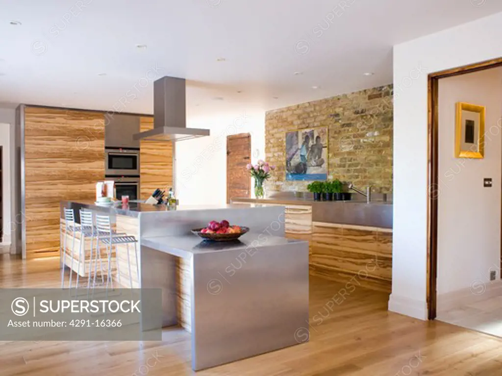 Stainless-steel island unit in large modern kitchen with wooden flooring