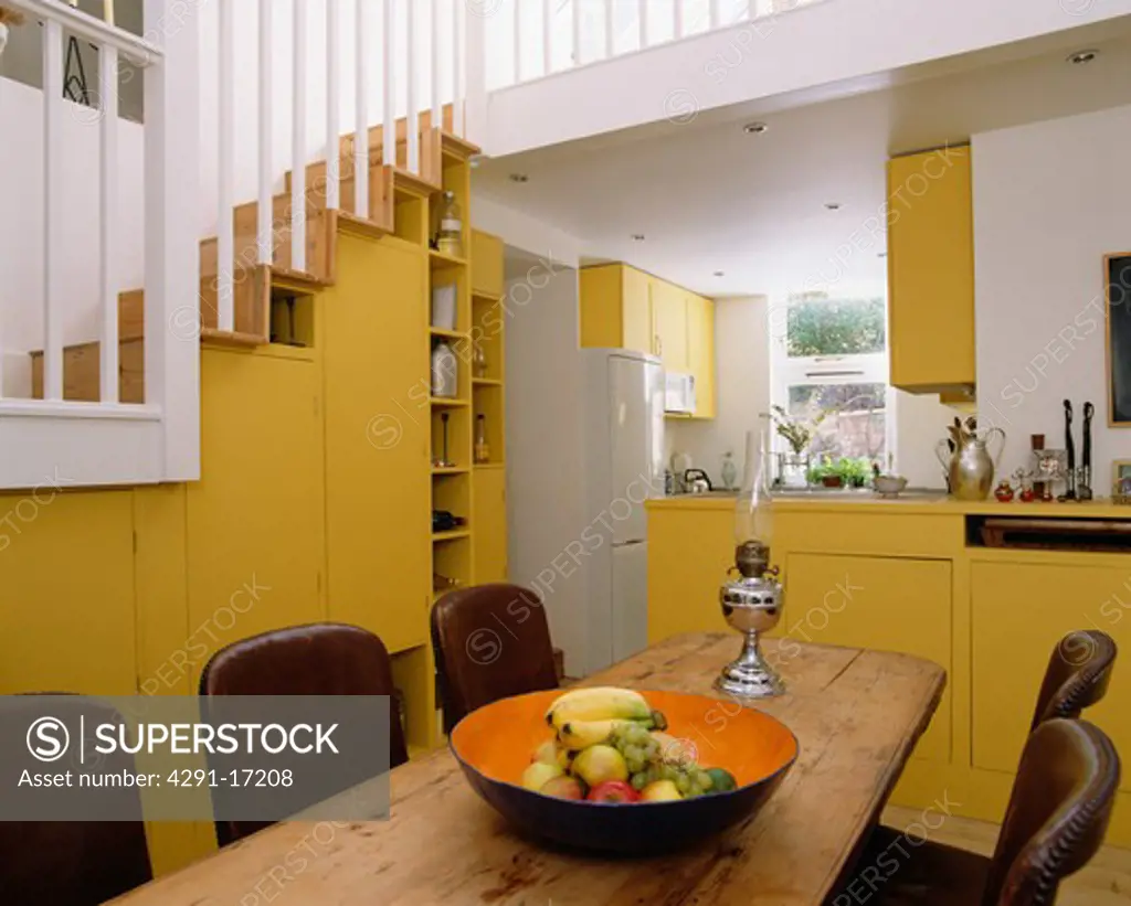 Wooden table in modern yellow kitchen dining room