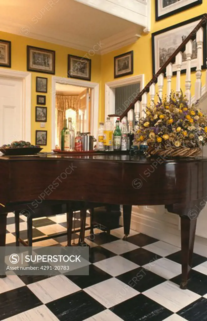 Grand piano and black and white chequerboard vinyl flooring in yellow hall