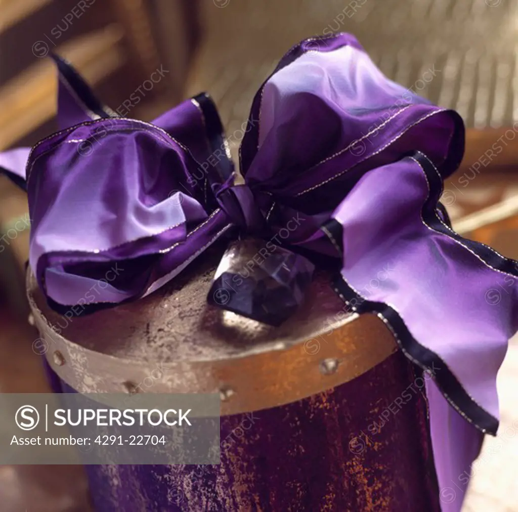 Purple and gold box topped with a large purple ribbon tied in a bow