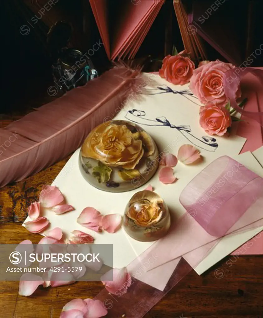 Still-Life of pink roses and rose petals with rose paper-weight on cream writing paper