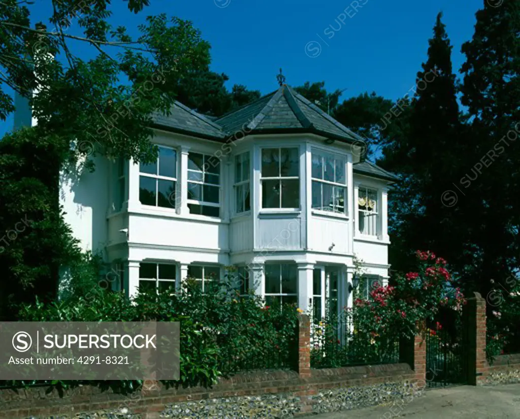 White Edwardian house with metal railings on brick wall in front of the house