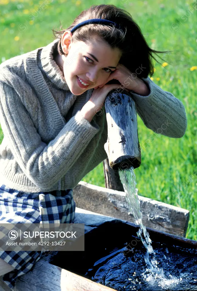 Woman sitting by a fountain at the countryside