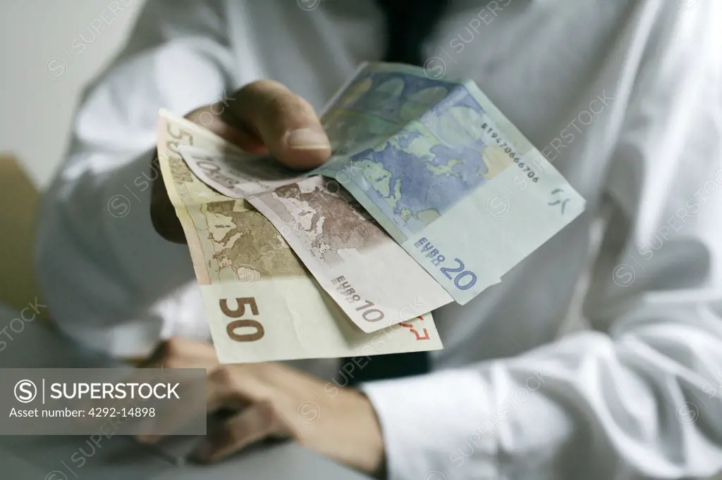 Man's hand holding euro banknotes