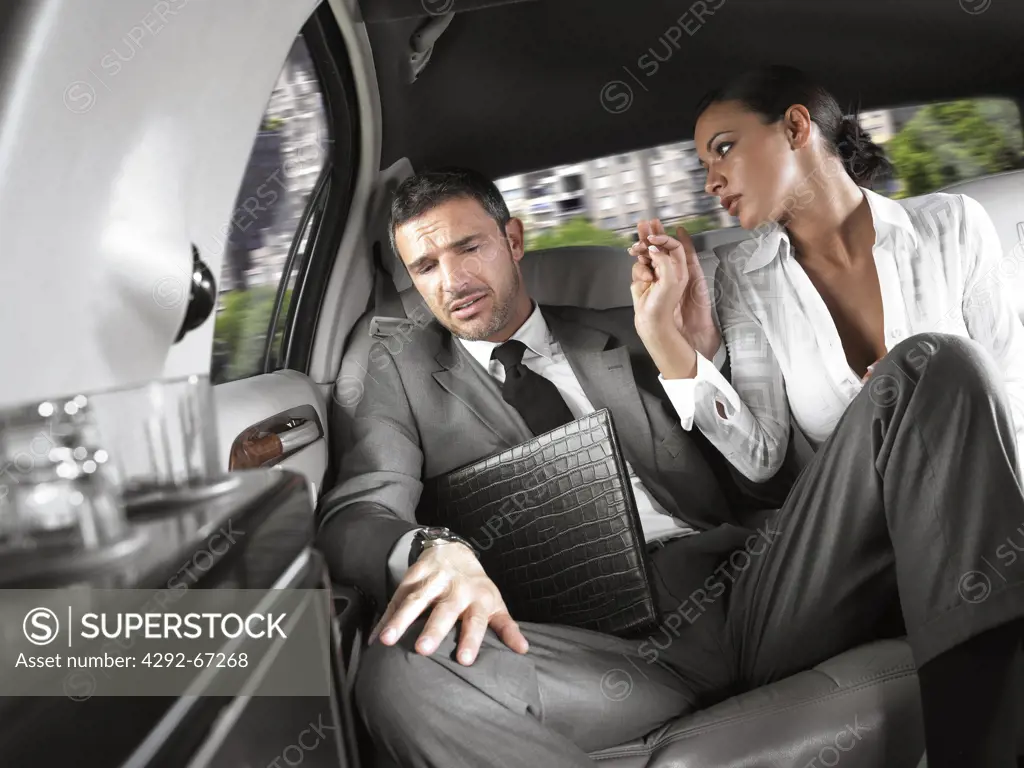 Businessman and businesswoman sitting in the back seat of a limousine