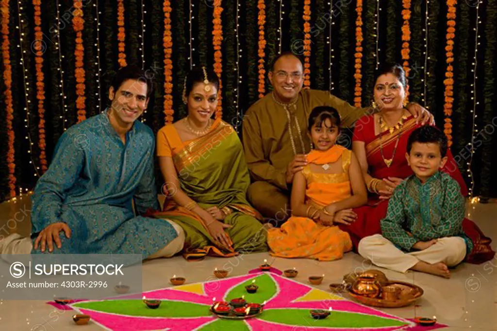 Three generation Indian family infront of rangoli