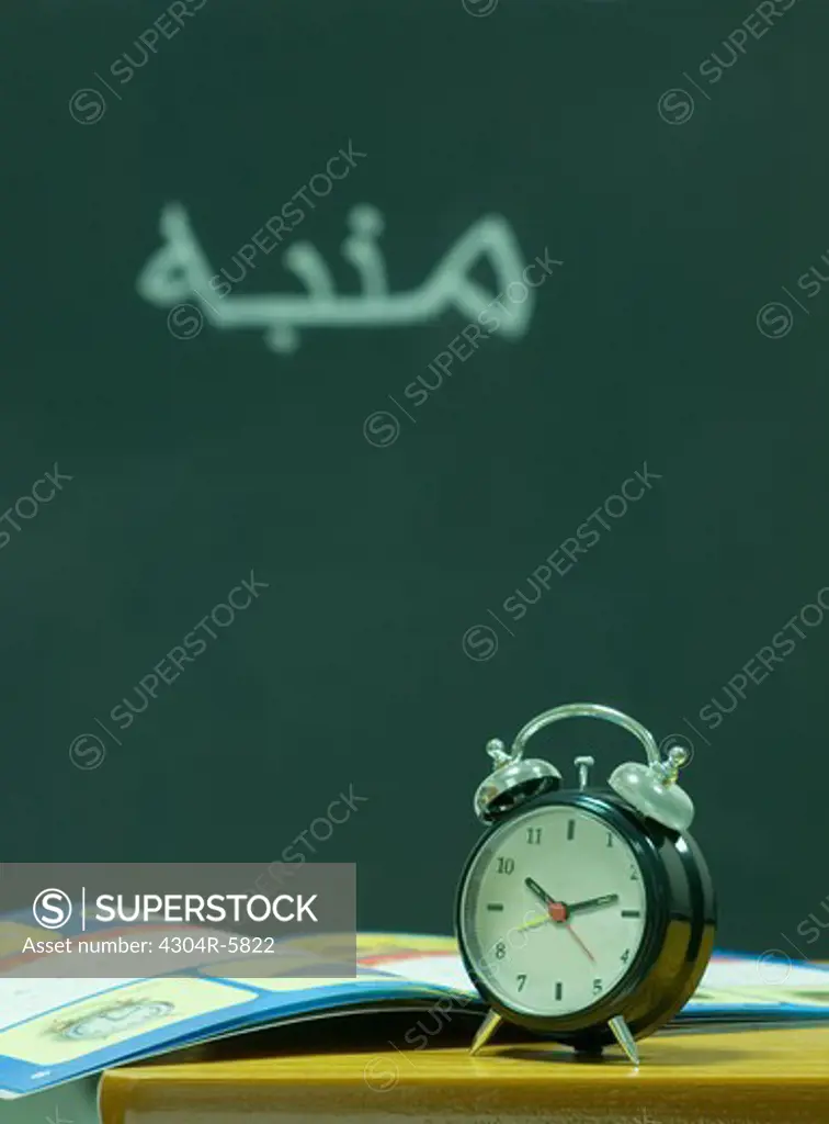 Book and clock kept on table in classroom, close-up