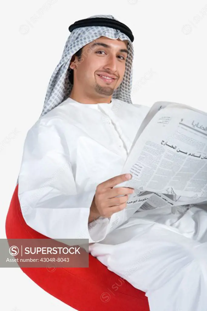 Young man holding newspaper, smiling, portrait