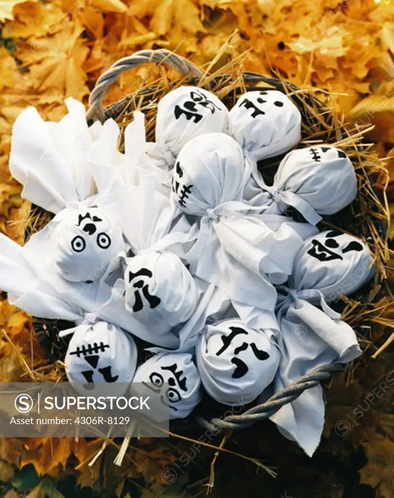 White ghost dolls in basket on yellow leaves