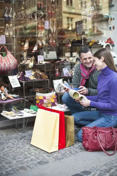 Couple holding shoes outside shop