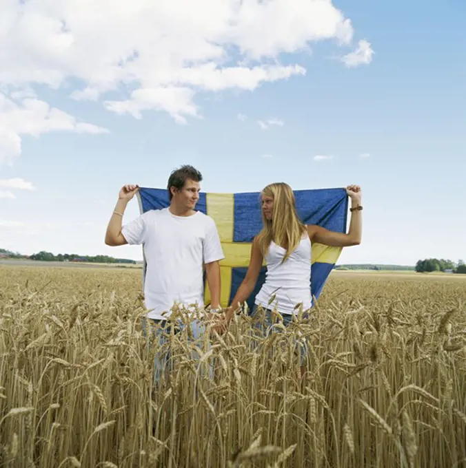 Couple holding Swedish flag in field