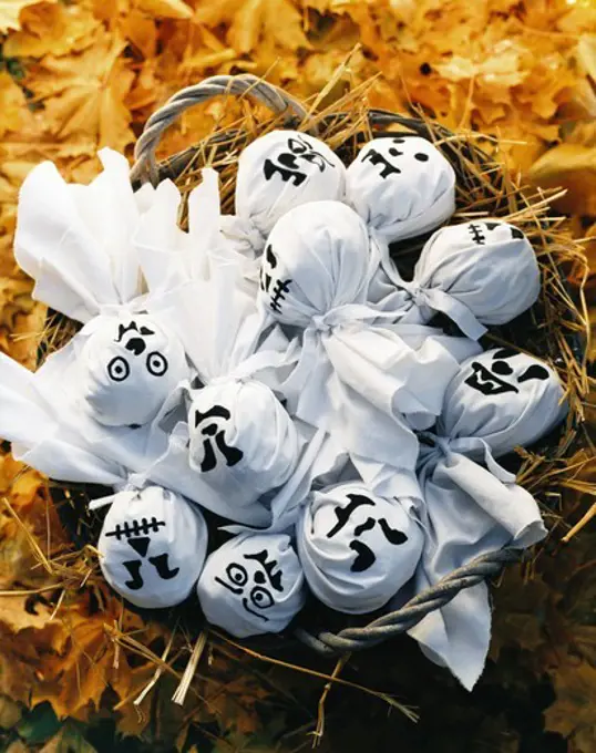 White ghost dolls in basket on yellow leaves