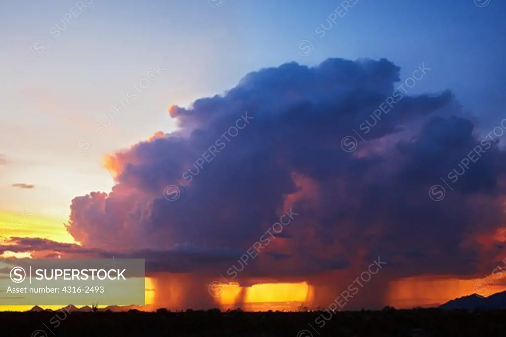 A thunderstorm, or cumulonimbus, unleashes twin curtains of rain over Tucson, Arizona at sunset.