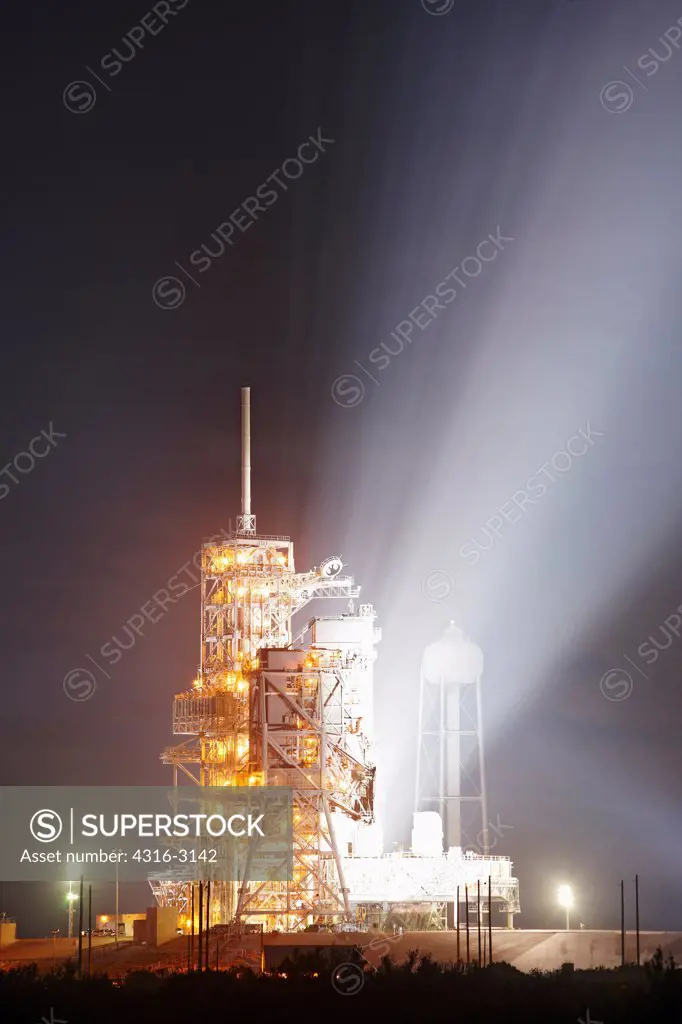 Powerful xenon floodlights illuminate the early morning sky from the launch tower at Pad 39A, Kennedy Space Center, Florida, after the launch of Space Shuttle Endeavour on STS-130.