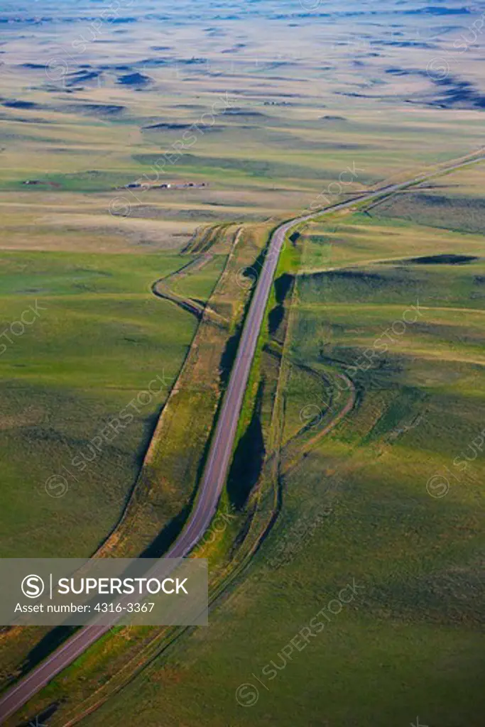 An aerial view of a paved road through green plains, in eastern Colorado.