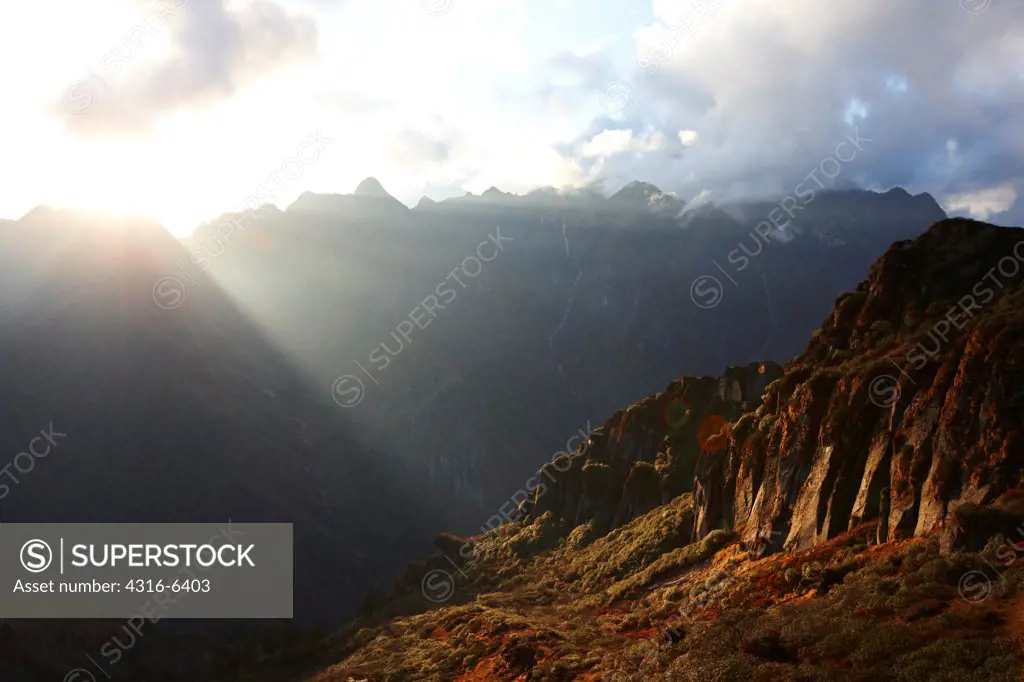 Nepal, Himalaya, Makalu-Barun National Park, sun rays coming through clouds near Shipton Pass, sunset