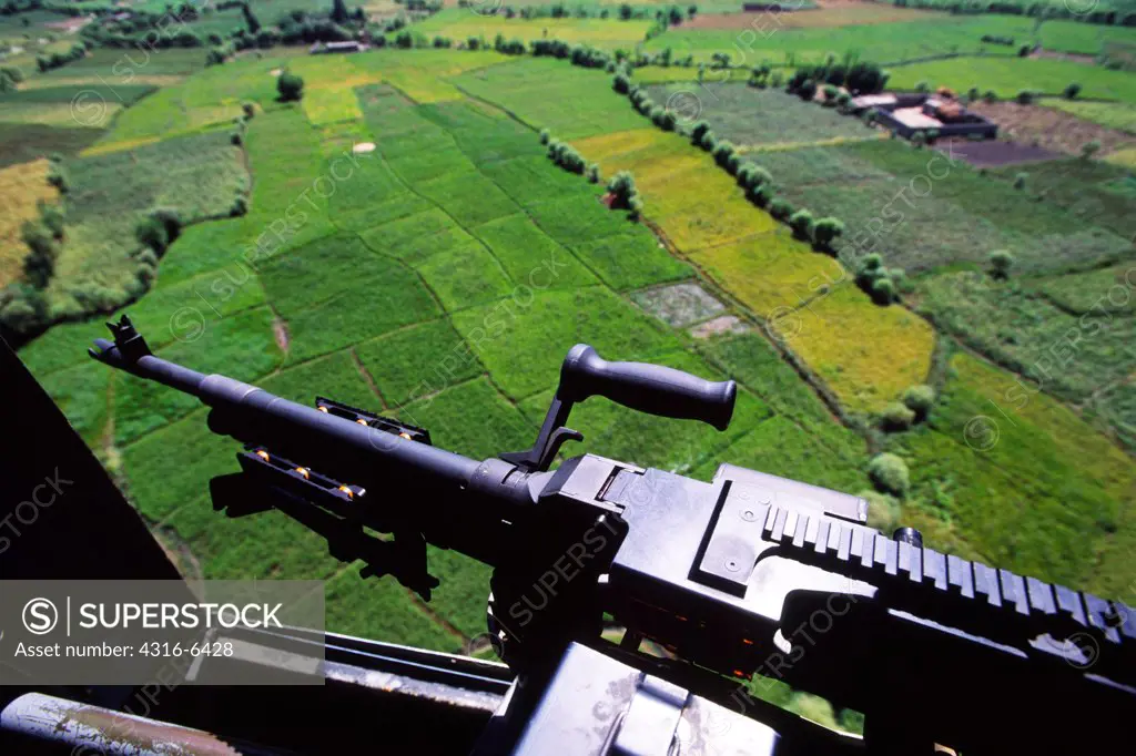 Afghanistan, fields seen from Chinook helicopter, machine gun in foreground