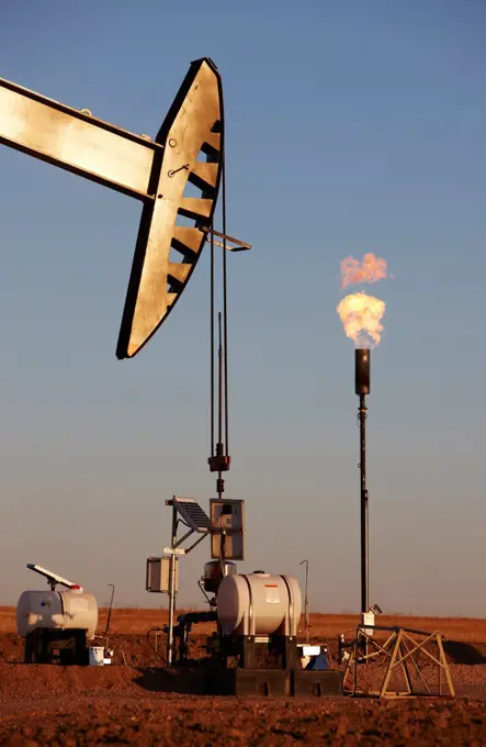 Oil well pumpjack and gas flare in the eastern plains of Colorado, USA