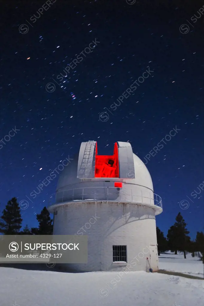 The 42" telescope glows softly red in this time exposure of the dome illuminated by a partial moon. Just above the dome the constellation Orion is rising into the winter sky. The 42" telescope is one of several that Lowell Observatory uses on Anderson Mesa, located just south of Flagstaff, Arizona.