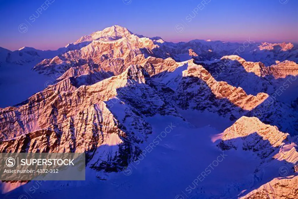 An aerial view of winter sunset illuminating peaks of the Alaska Range east of the Kahiltna Glacier leading toward Mount Hunter and Mount McKinley, Denali National Park, Alaska.