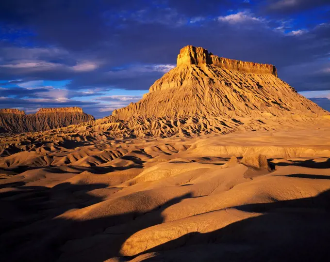 Morning light illuminating Factory Butte, badlands of Mancos shale capped by harder Ferron Sandstone, B.L.M. land northwest of Hanksville, Utah.