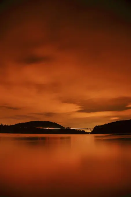 A Night Photograph of Traffic on the Deception Pass Bridge with the Sky Lit By The City Light Of Mt Vernon From North Beach in Deception Pass State Park in Washington