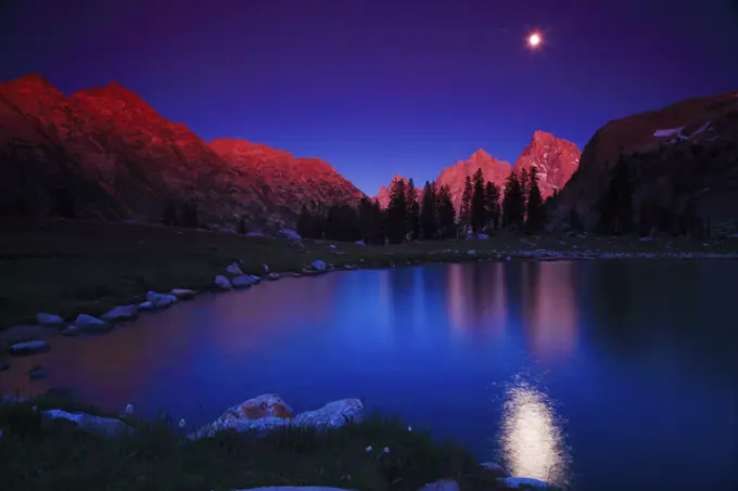 Aplenglow With The Moon and Grand Tetons Over Lake Solitude in the Backcountry of Grand Teton National Park in Wyoming