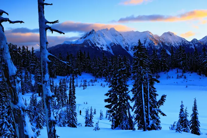 A winter scene at sunrise over a frozen Picture Lake, in the Heather Meadows, with the Nooksack Ridge in the distance.