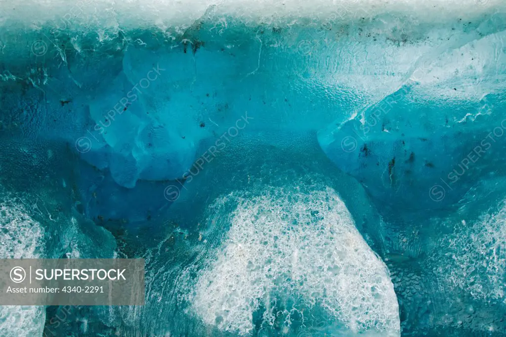 Close up of a blue glacial iceberg floating off the coast of Svalbard, Norway, in summertime.