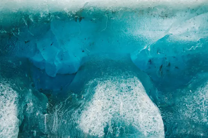 Close up of a blue glacial iceberg floating off the coast of Svalbard, Norway, in summertime.