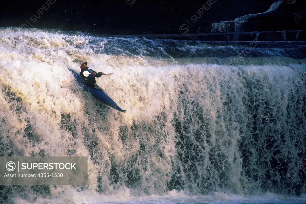 A kayaker kayaks over a waterfall.