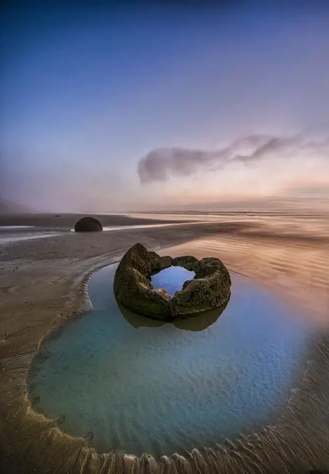 The Moeraki Boulders are large spherical boulders lying along a stretch of Koekohe Beach on the Otago coast of the South Island in New Zealand