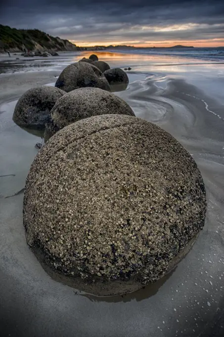 The Moeraki Boulders are large spherical boulders lying along a stretch of Koekohe Beach on the Otago coast of the South Island in New Zealand