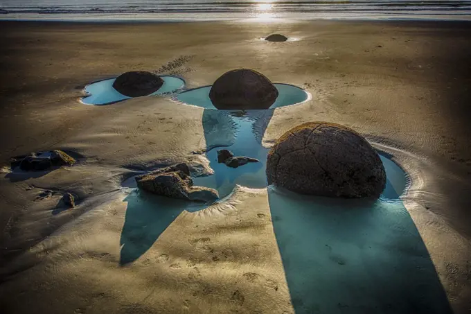 The Moeraki Boulders are large spherical boulders lying along a stretch of Koekohe Beach on the Otago coast of the South Island in New Zealand