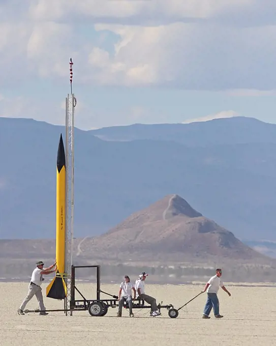 A small group of people pull a yellow rocket 'The Minnesota Youbetcha', out to the launch range at BALLS, an experimental rocketry event in the Black Rock Desert of northern Nevada.