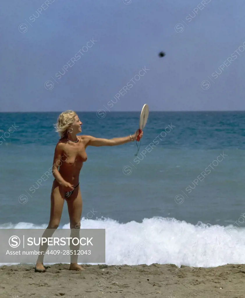 MUJER EN TOPLESS JUGANDO AL TENIS. - SuperStock