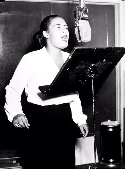 American jazz singer Billie Holiday singing into a microphone at a Decca recording session, 1946.