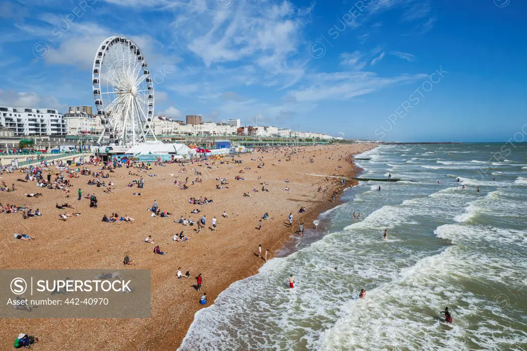 Tourists and ferris wheel on the beach, Brighton Beach, Brighton, East Sussex, England