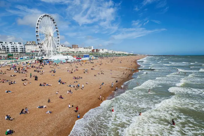 Tourists and ferris wheel on the beach, Brighton Beach, Brighton, East Sussex, England