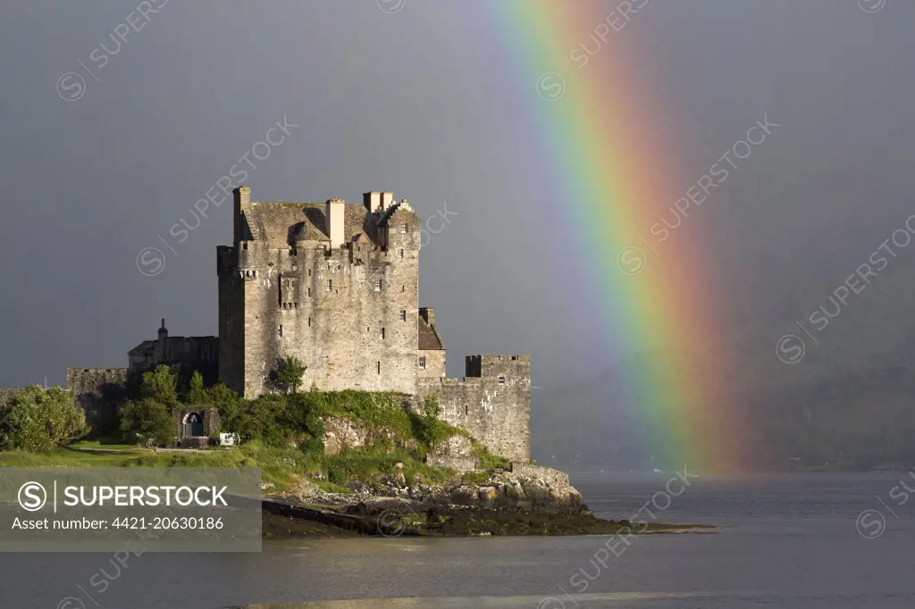 View of restored castle on tidal island in sea loch with rainbow, in evening sunlight, Eilean Donan Castle, Loch Duich, Ross and Cromarty, Highlands, Scotland, July