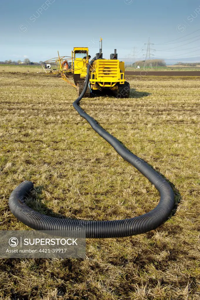 Field drainage, continuous pipe laying machine working in arable field, Pilling, Lancashire, England, march