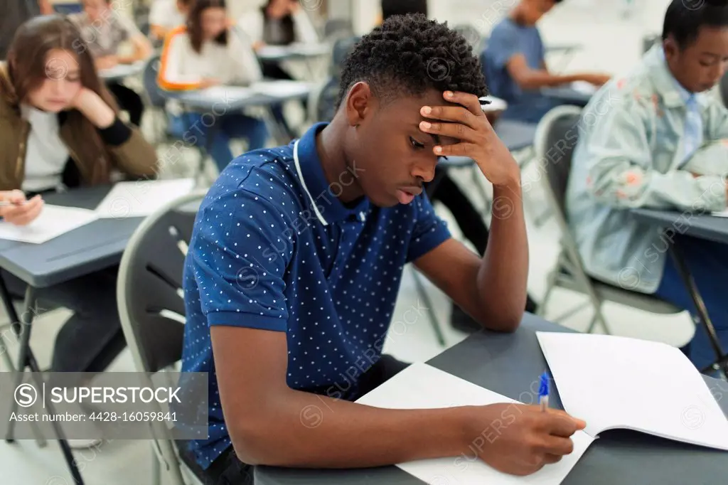 Focused high school boy taking exam at desk in classroom